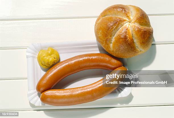 two wieners on a paper plate with a dollop of mustard; roll - roll on bildbanksfoton och bilder