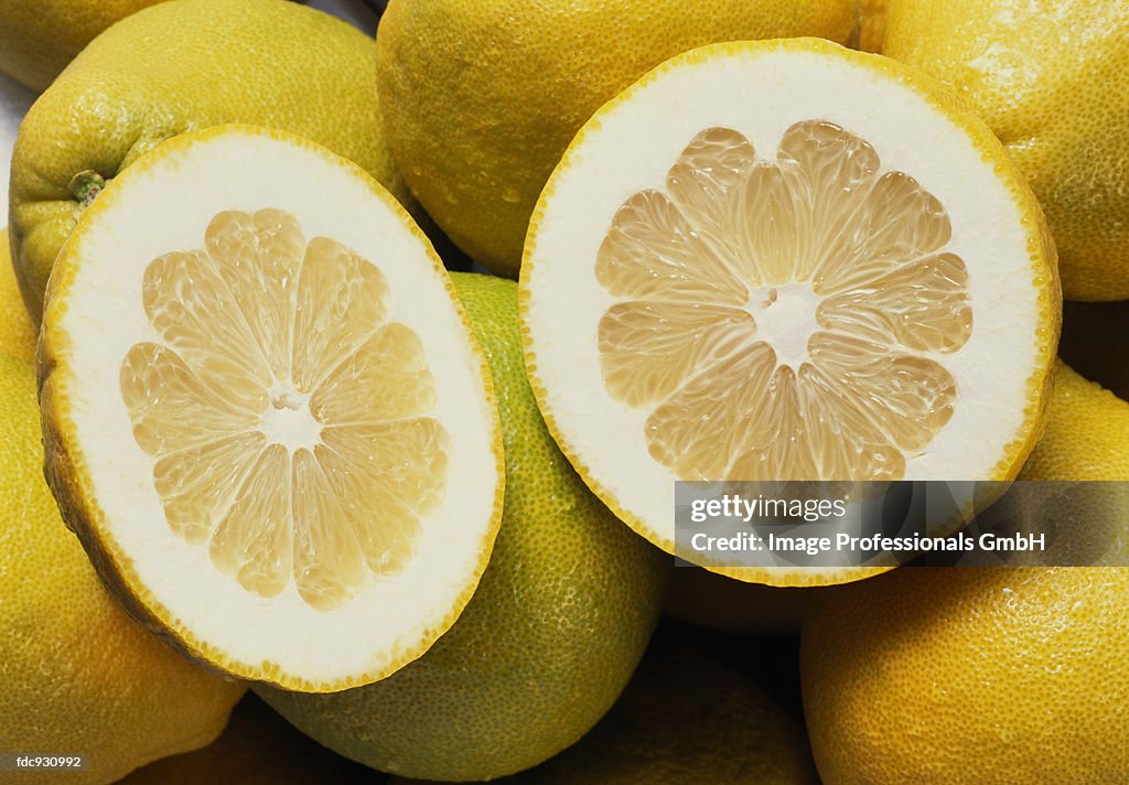 Several whole pomelos and two pomelo halves (close-up)