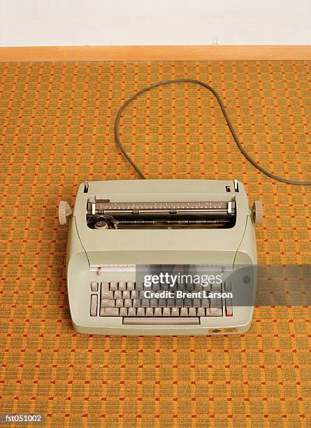 a typewriter centered on a retro carpet - gestalt stock-fotos und bilder