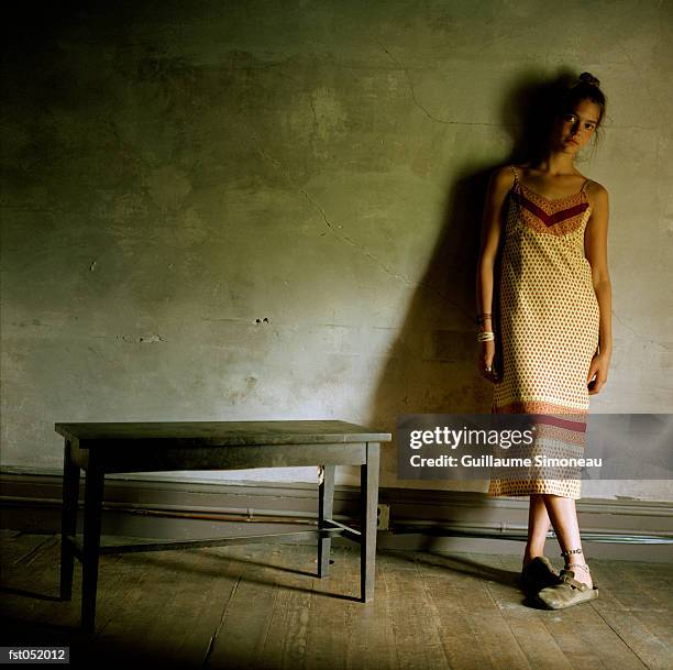 a young woman stands with her legs crossed by a small bench - simoneau stock-fotos und bilder