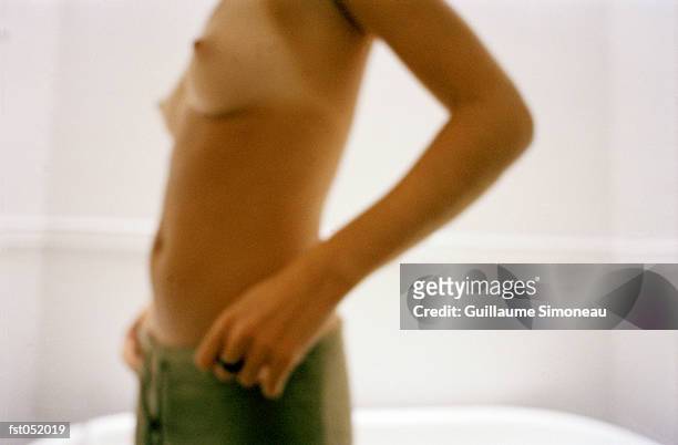 a shirtless young woman posing in a bathroom - simoneau stock-fotos und bilder