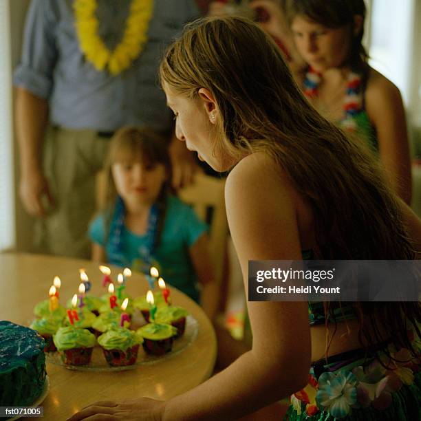 a girl blowing out the candles at a birthday party - heidi stock-fotos und bilder