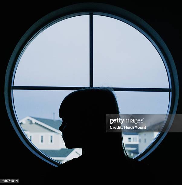 a child in profile in a round window - heidi stock-fotos und bilder