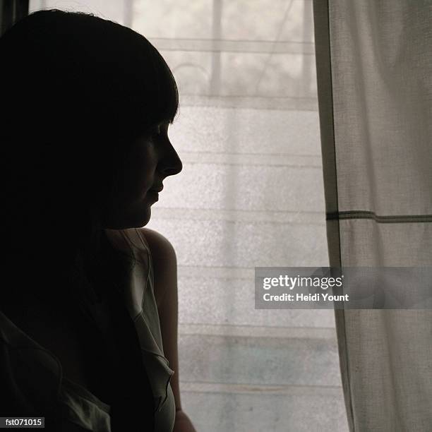 a woman standing next to a window - heidi stock-fotos und bilder