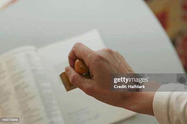 a hand holding a stamp - stamp foto e immagini stock