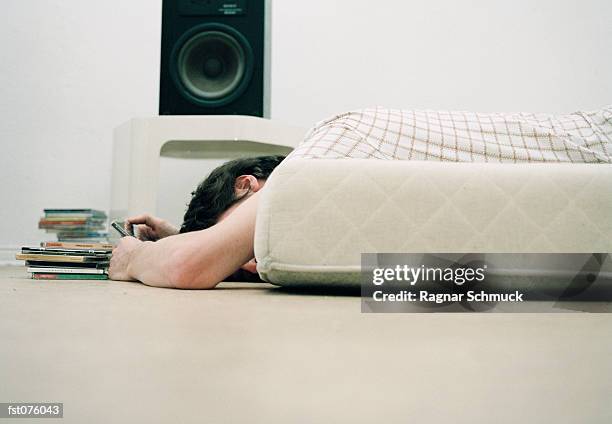 a person lying on a bed, below a speaker - schmuck - fotografias e filmes do acervo