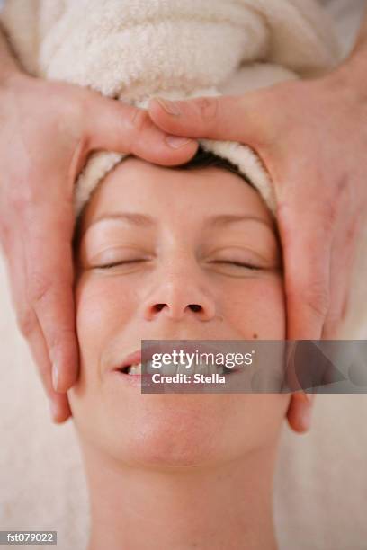 a massage therapist massaging a woman?s face - stella stockfoto's en -beelden