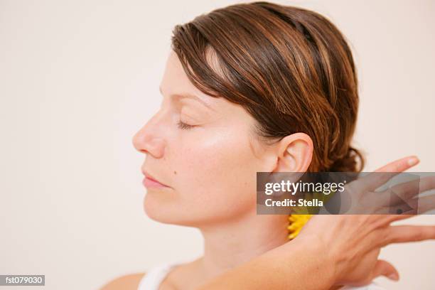 a woman massaging her neck with a massage ball - stella stockfoto's en -beelden