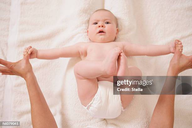 an adult stretching a baby?s arms - stella stockfoto's en -beelden