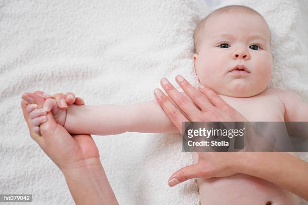 an adult stretching a baby?s arm - stella stockfoto's en -beelden