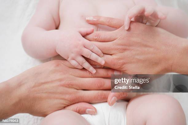 an adult massaging a baby?s stomach - stella stock pictures, royalty-free photos & images