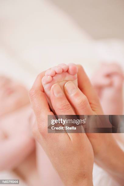 an adult massaging a baby?s foot - stella stock-fotos und bilder