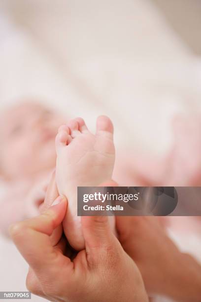 an adult massaging a baby?s heel - stella stock-fotos und bilder