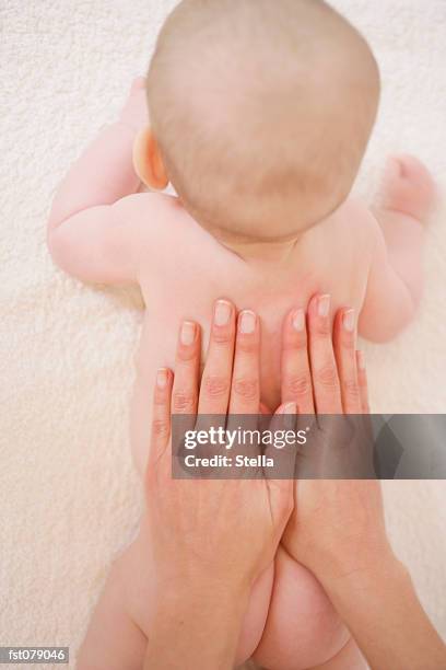 an adult touching a baby?s back - stella stock-fotos und bilder