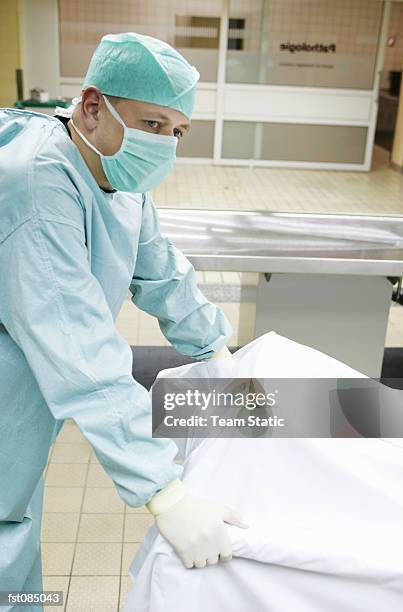 doctor pushing a gurney - autopsie stock-fotos und bilder