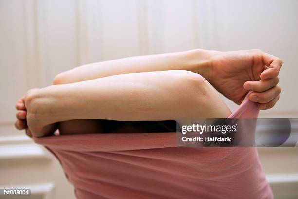 woman taking off sweater - elbow stockfoto's en -beelden