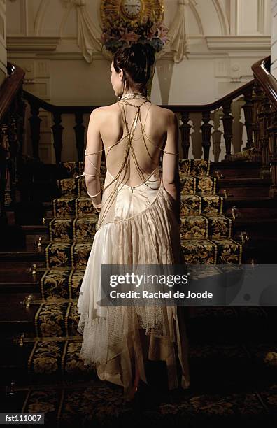 woman in evening gown walking up stairs - woman in evening dress stock-fotos und bilder
