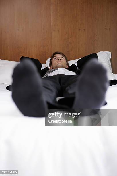 businessman lying down on bed - stella stock-fotos und bilder