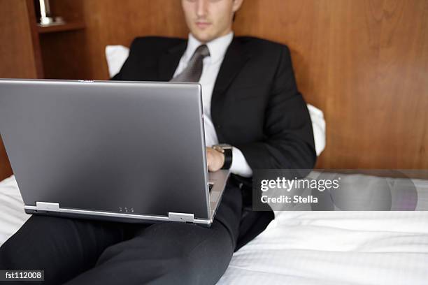 businessman using laptop computer in bed - stella stock-fotos und bilder