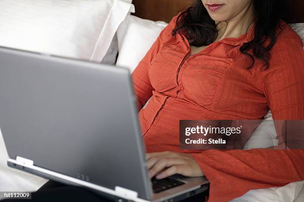 woman using laptop computer in bed - stella stock-fotos und bilder