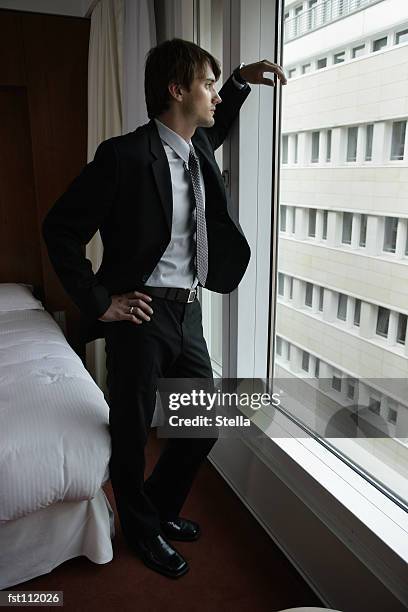 man in suit standing at window - stella stock-fotos und bilder