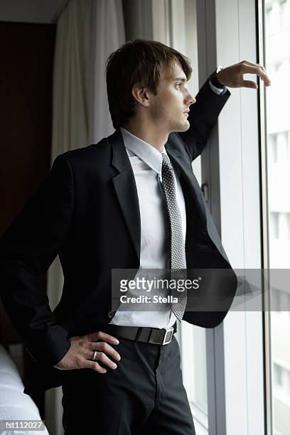 man in suit standing at window - stella stock pictures, royalty-free photos & images