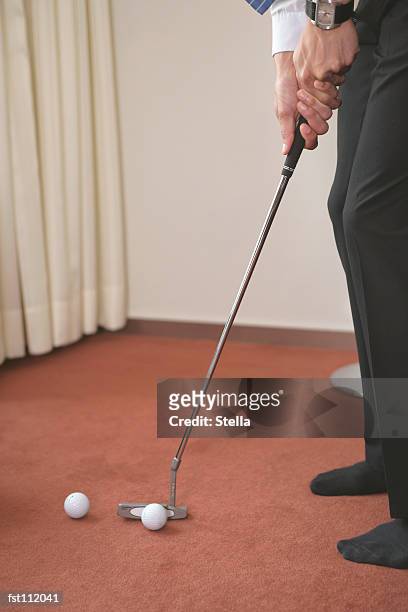 man playing golf inside on carpet - stella stockfoto's en -beelden