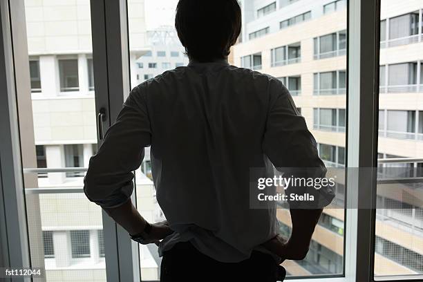 businessman standing at window - stella stockfoto's en -beelden