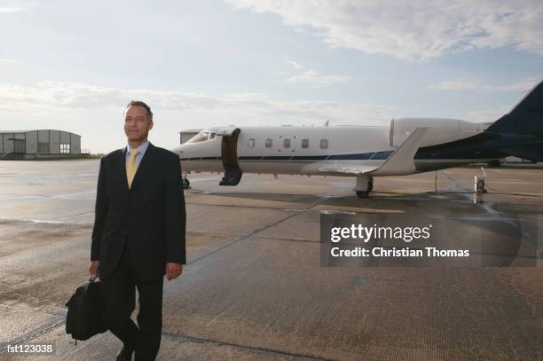 businessman standing in front of a private airplane - aviación civil fotografías e imágenes de stock