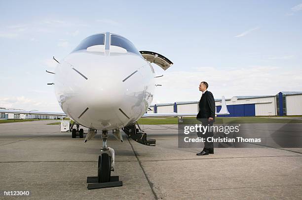 businessman standing next to an airplane - thomas photos et images de collection