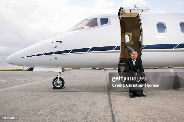 businessman sitting on a private airplane?s steps - thomas photos et images de collection