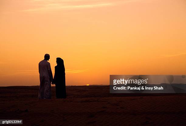 young arab couple watching sunset - shah stock-fotos und bilder