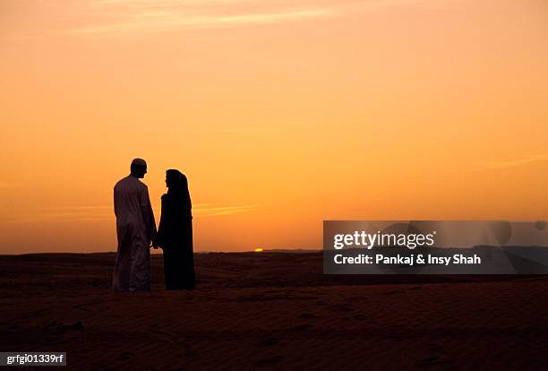 young arab couple watching sunset - dubai sunset desert stock pictures, royalty-free photos & images