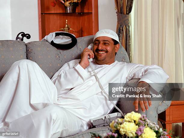 arab  man relaxing on sofa at home - shah stock-fotos und bilder