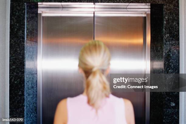 woman waits in front of lift - ascensor fotografías e imágenes de stock
