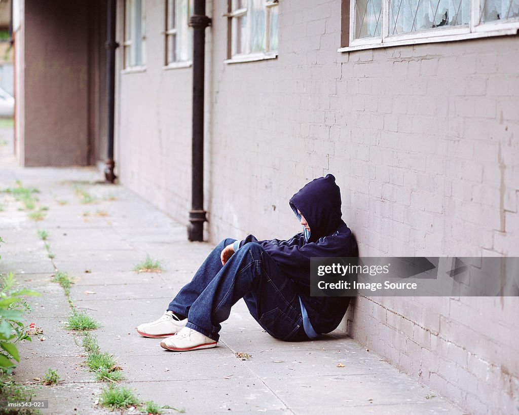 Teenage boy sitting against wall