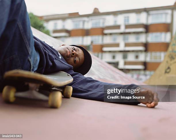 boy lying on skateboard ramp - skateboard fall stock-fotos und bilder