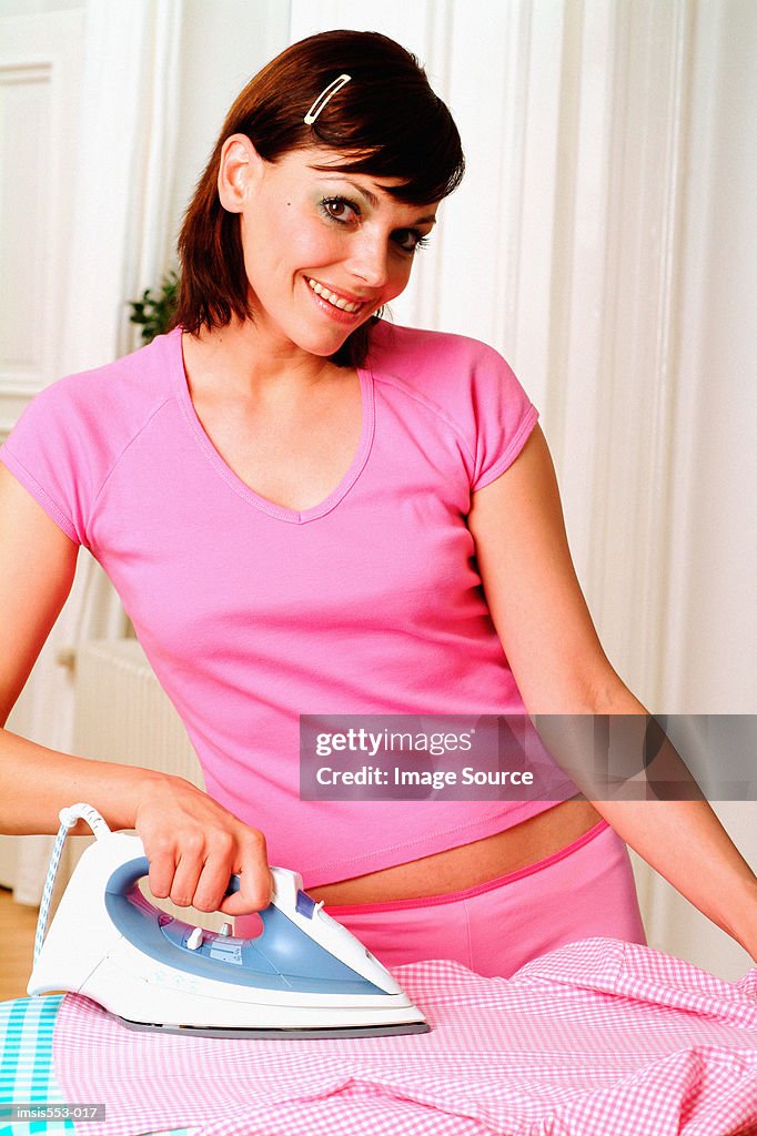 Young woman happily ironing