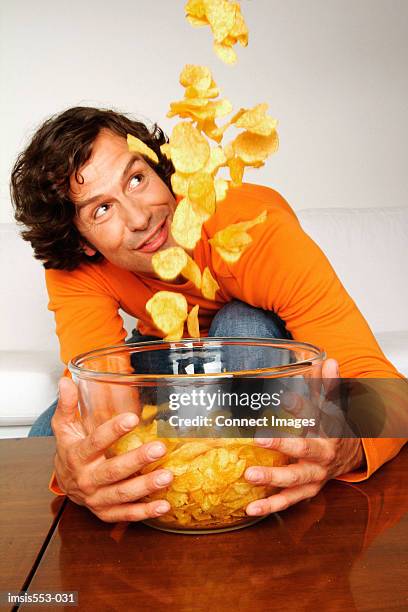 young man with bowl of crisps - snack bowl stock pictures, royalty-free photos & images