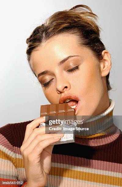 young woman eating chocolate - chocolate closed eyes stock-fotos und bilder