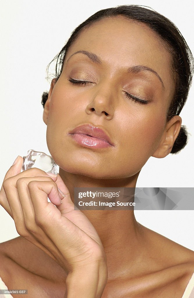 Woman holding ice cube on face