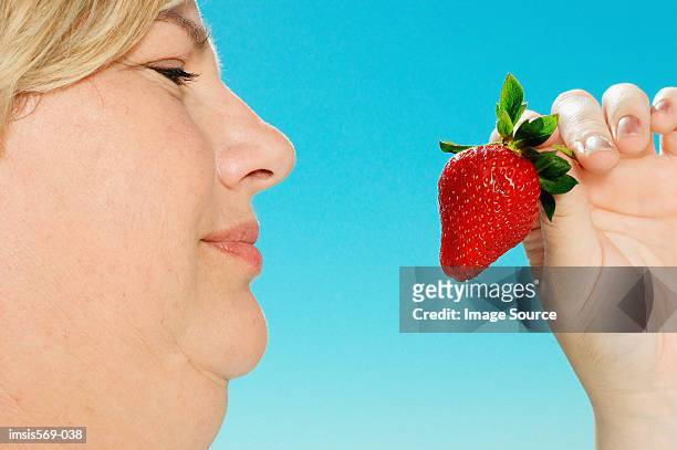 large woman looking at strawberry - double chin stock-fotos und bilder