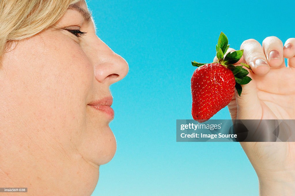 Large woman looking at strawberry