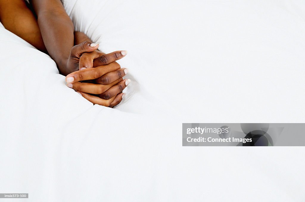 Couple holding hands in bed