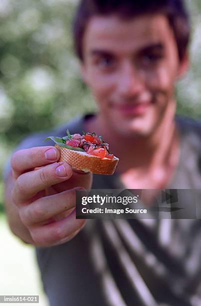 young man offering food. - man offering bread stock pictures, royalty-free photos & images