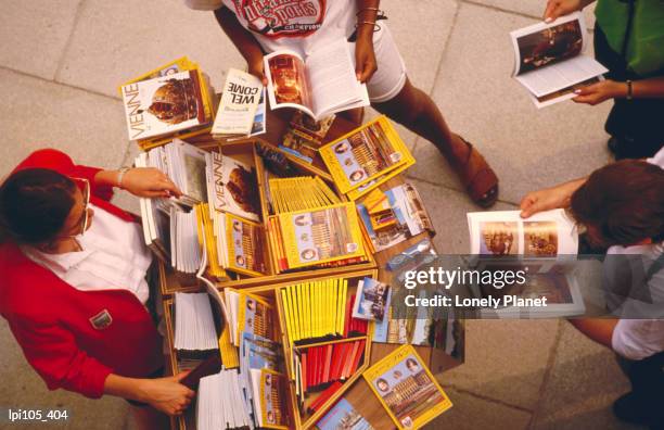 people browsing through maps and guides for sale. - commercial event stockfoto's en -beelden