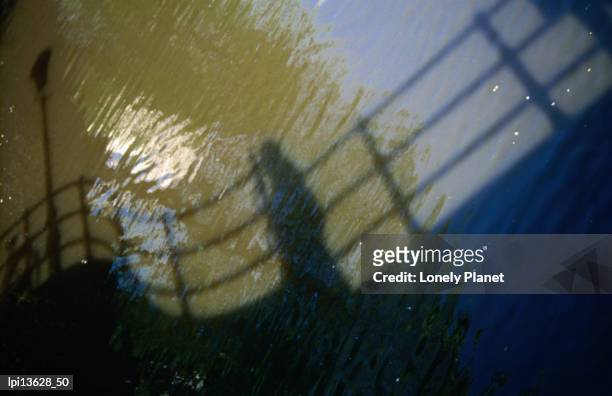 shadow of a person walking across bridge on canal water, southern canal belt, amsterdam, netherlands - north holland stock pictures, royalty-free photos & images