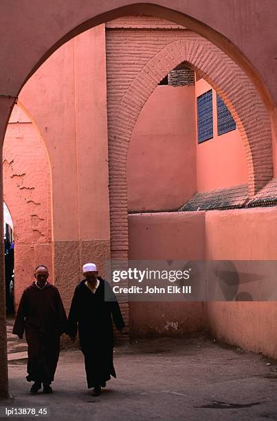 two men walking along a covered street in the medina, marrakech, morocco - africain stockfoto's en -beelden