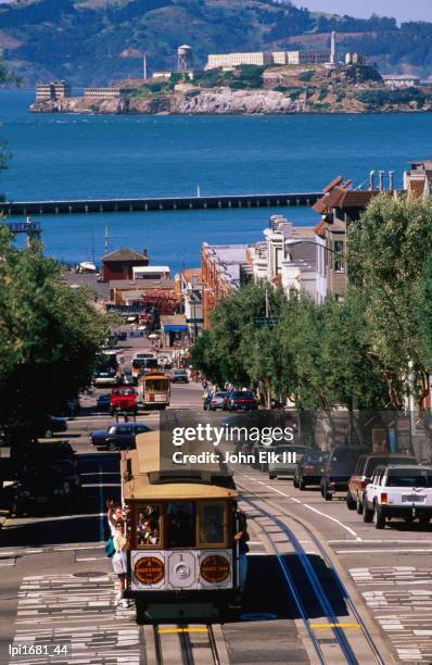 cable car and other traffic on street with alcatraz in distance, san franc1sco, united states of america - bucht-von-san-francisco stock-fotos und bilder