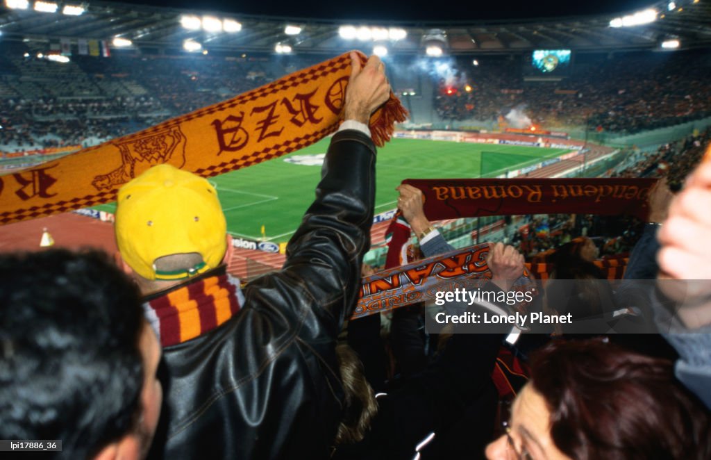 Soccer fans waving AS Roma scarves at AS Roma vs Ajax Amsterdam match at Champions League Game Stadio Olimpico, Rome, Italy